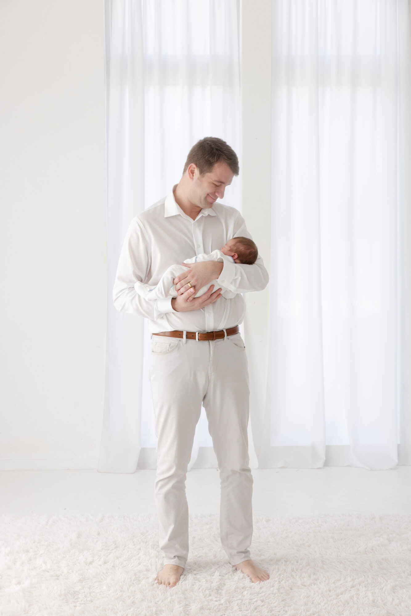 Dad lovingly looking at newborn baby boy during a Houston studio newborn photography session