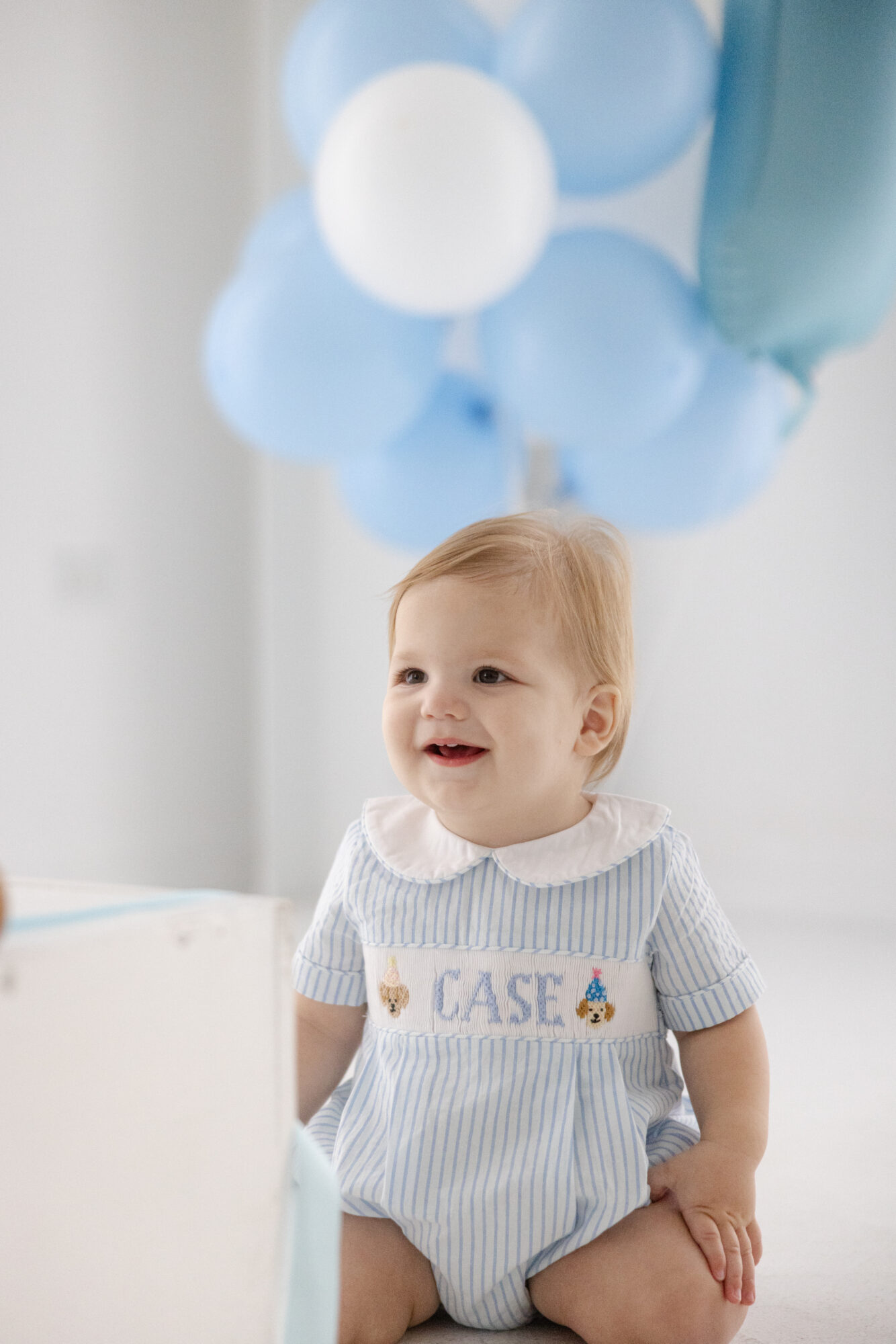 Baby boy sitting with blue balloons during a Houston first birthday photography session