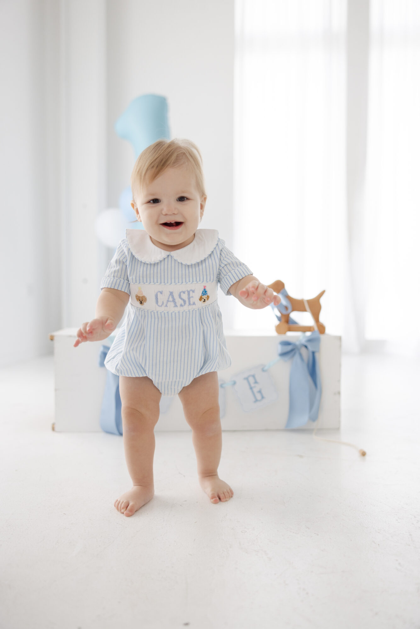 One year old boy standing in a bright Houston photography studio during his milestone session.