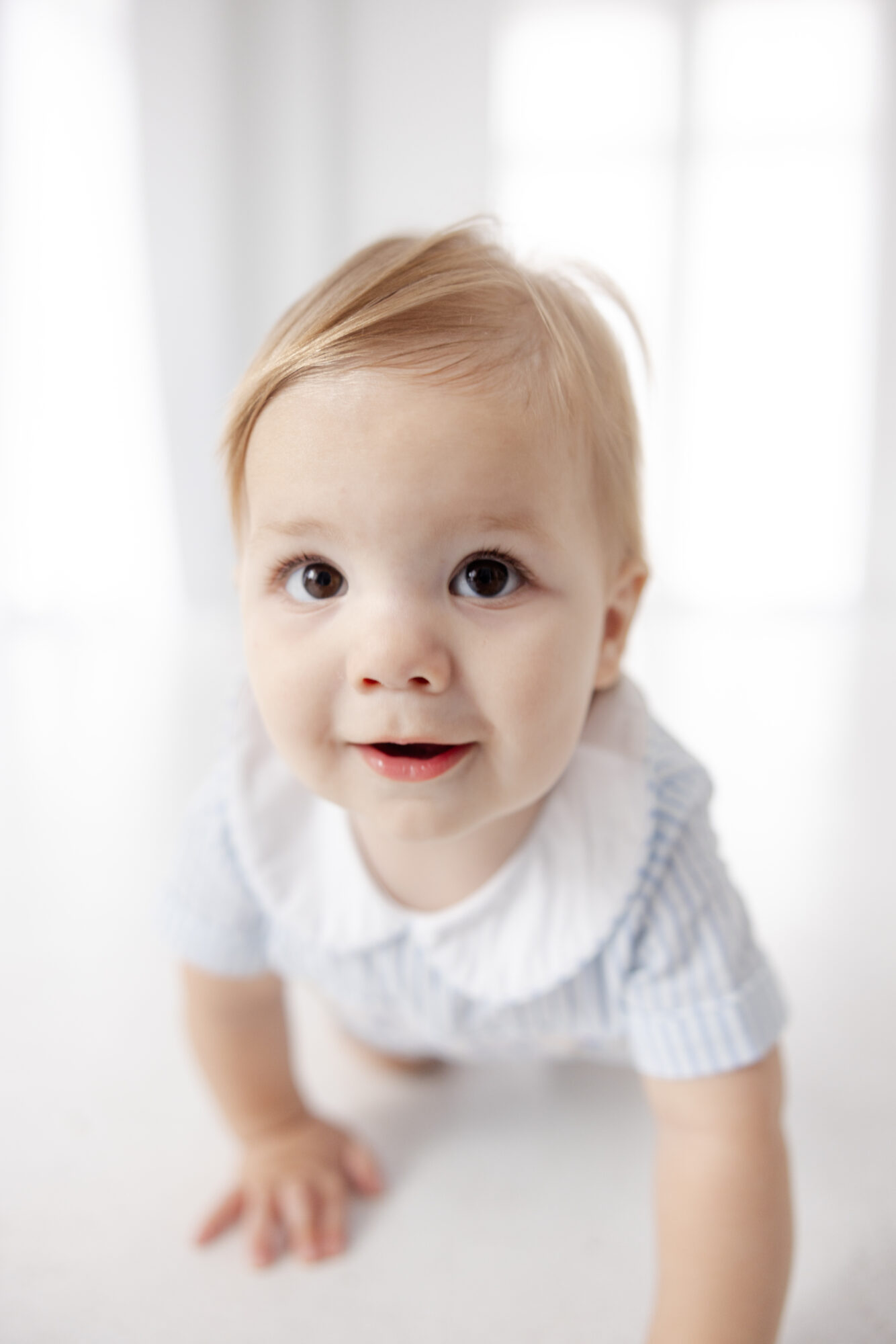Happy baby boy crawling toward the camera during a Houston first birthday photography session.