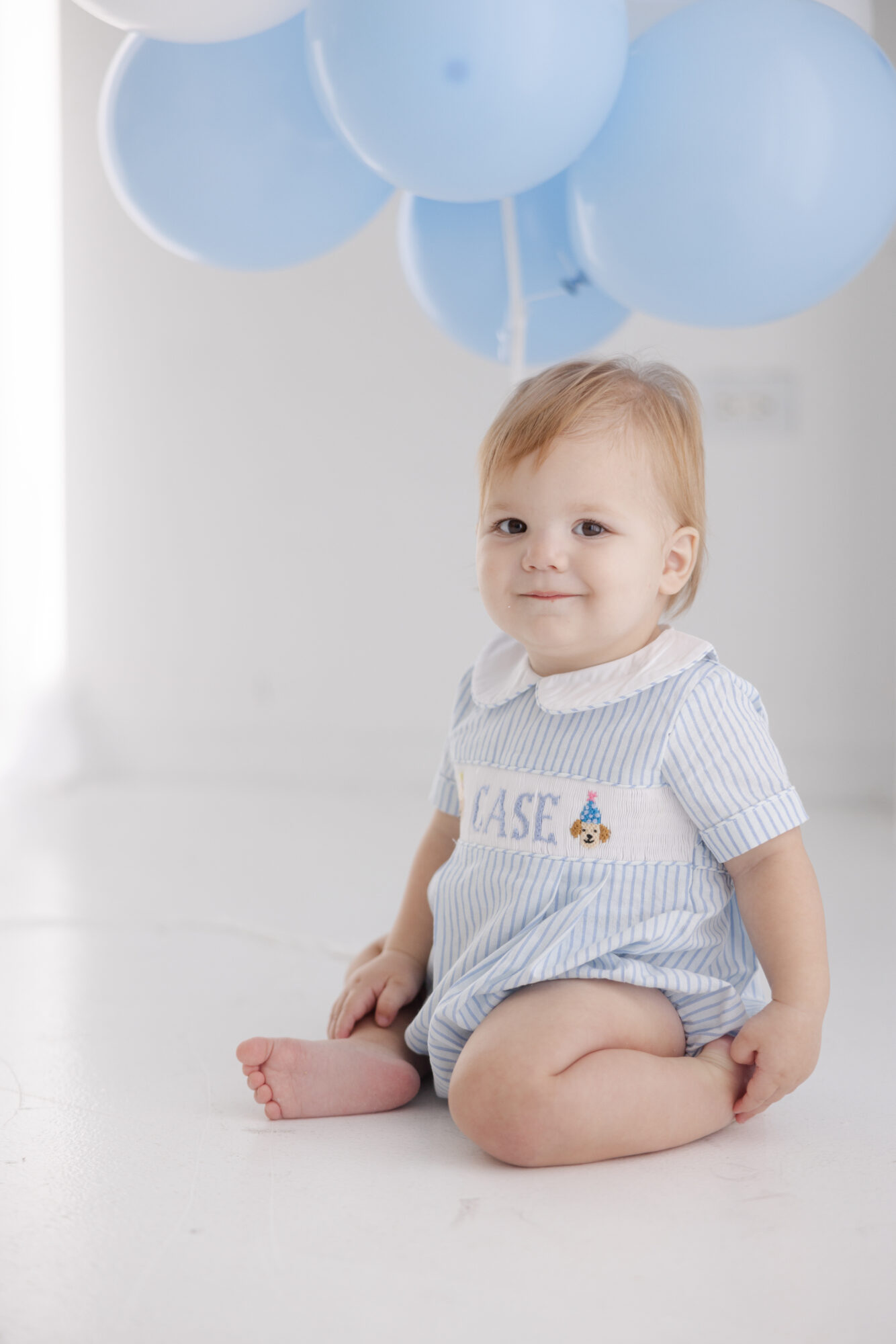 Close up portrait of a smiling baby boy during a Houston first birthday photography session.