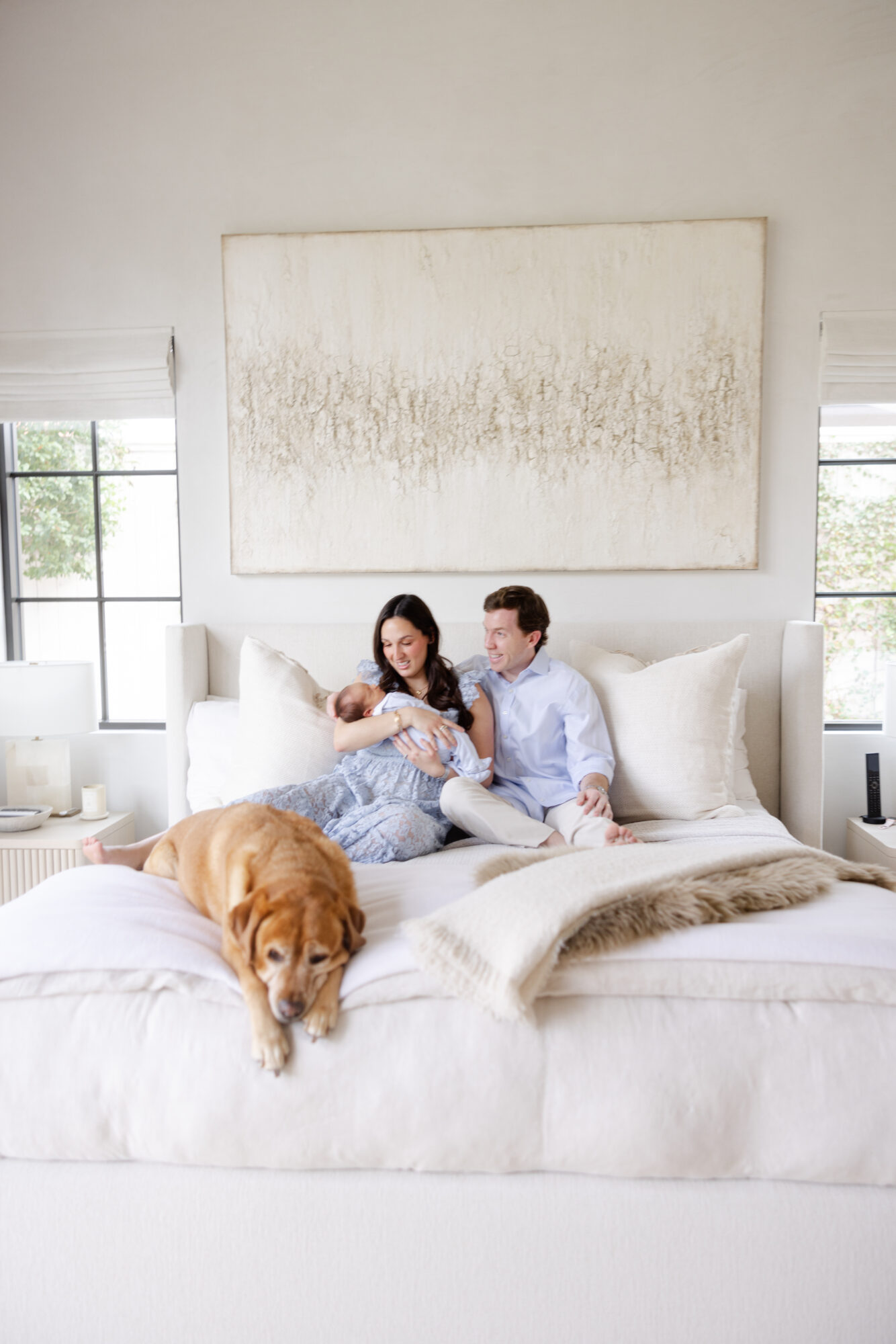 Family cuddling on the bed with their newborn baby and dog during an in home photography session in Houston.