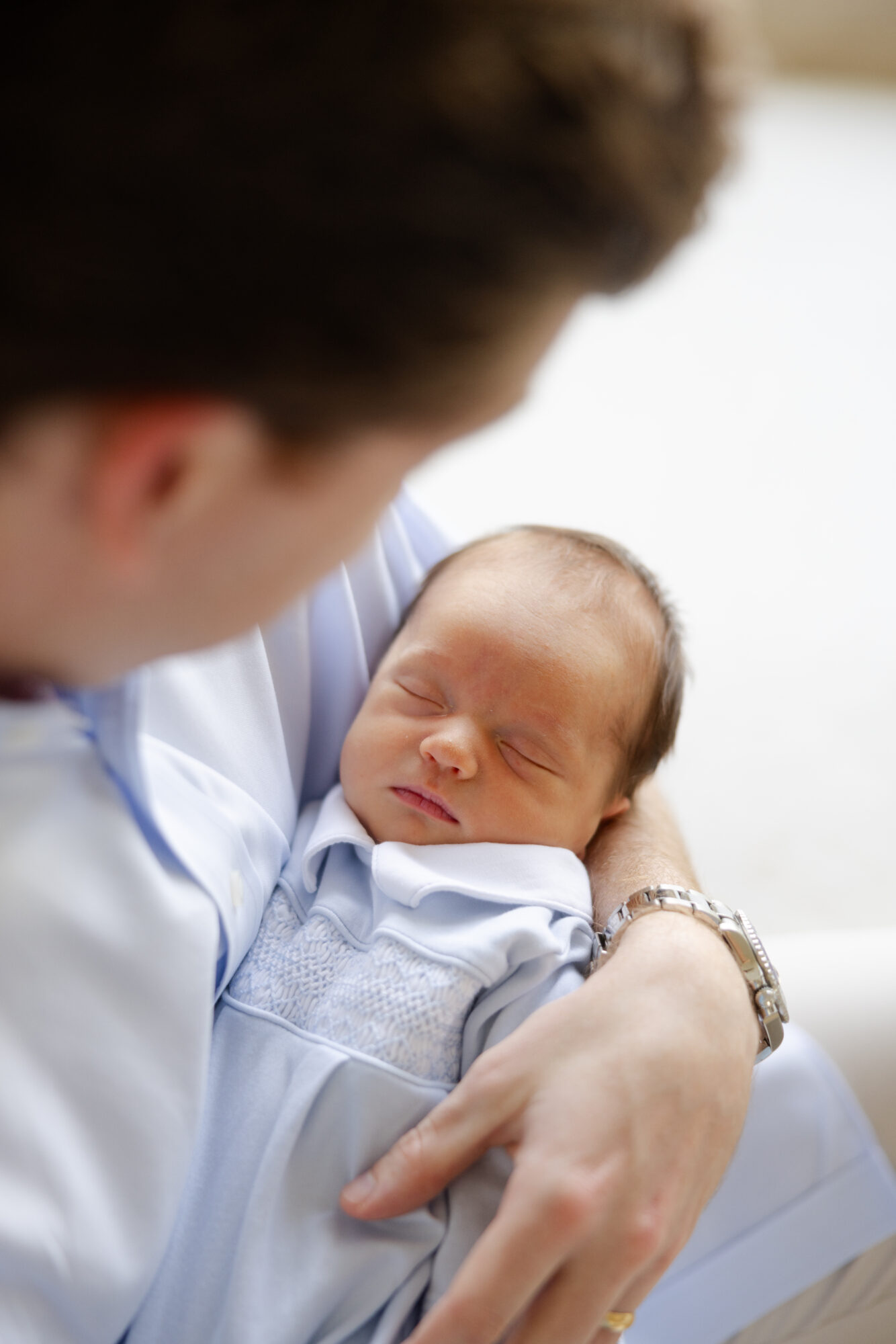 Dad looking down at his sleeping newborn son during an in home newborn session.