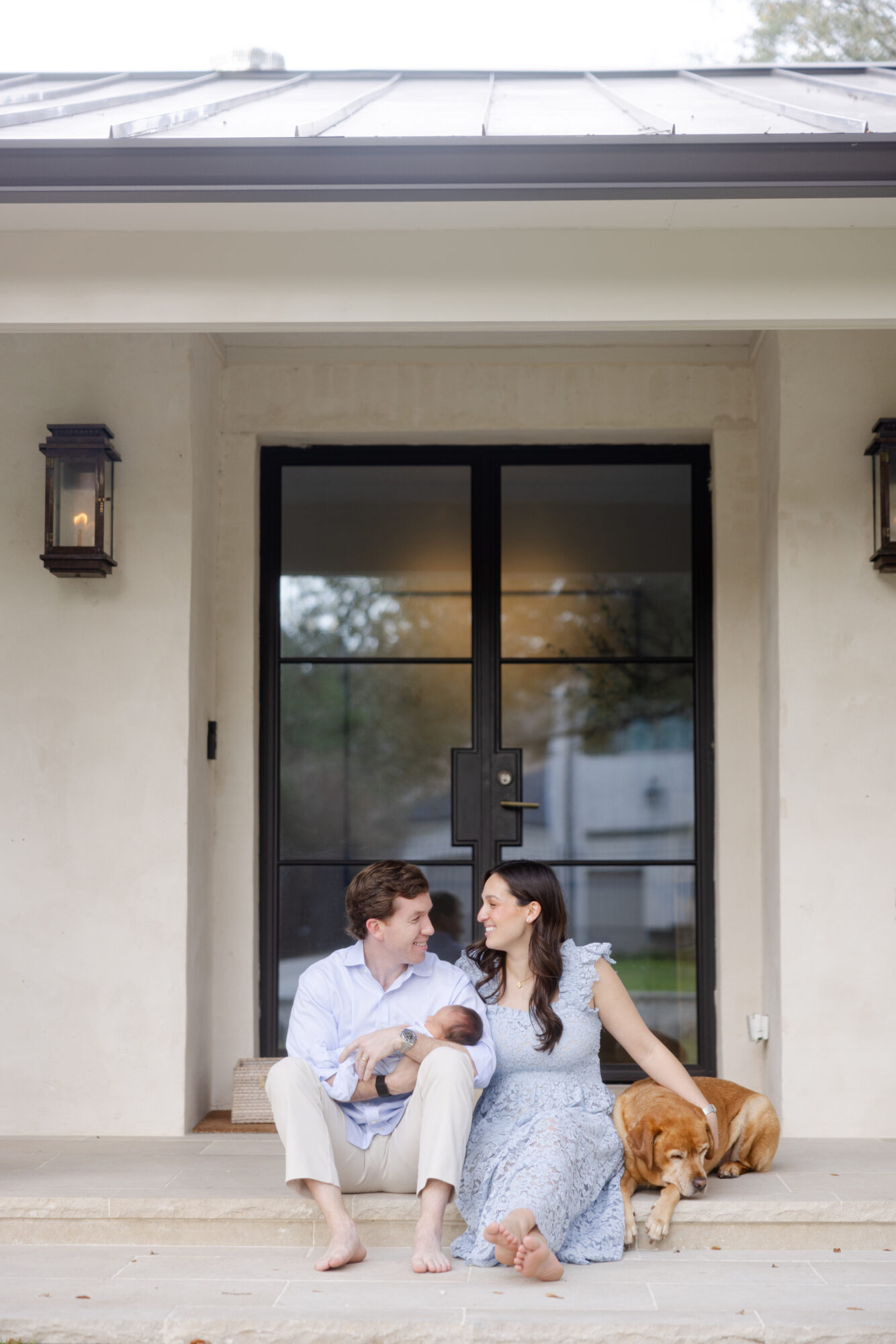 Parents sitting on their front porch with their newborn baby during a Houston lifestyle newborn session.